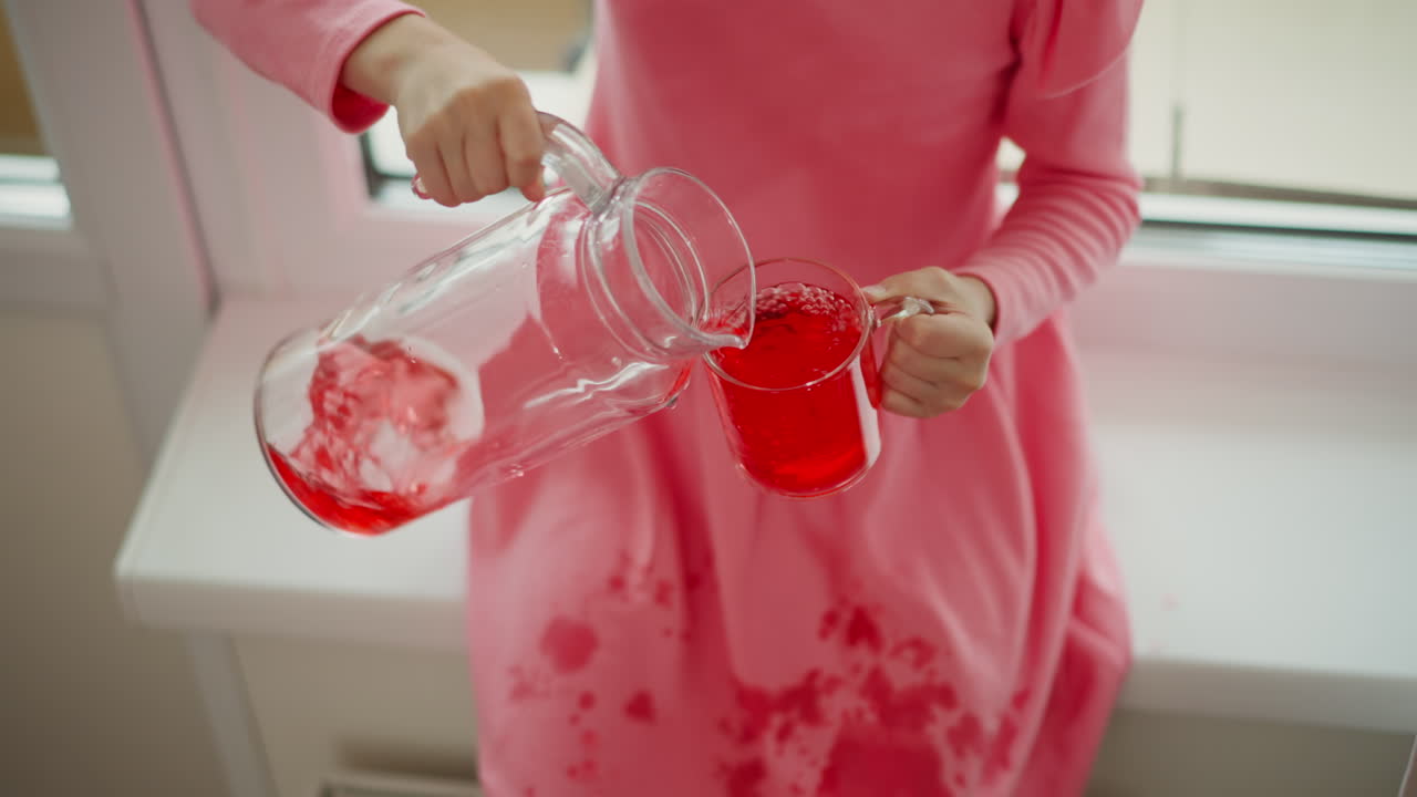 Child pouring red juice, messy accident