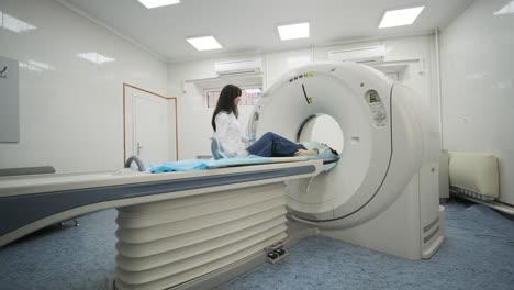 female patient is undergoing ct or mri scan under supervision of a radiologist in modern medical clinic. patient lying on a ct or mri scan bed, moving outside the machine.