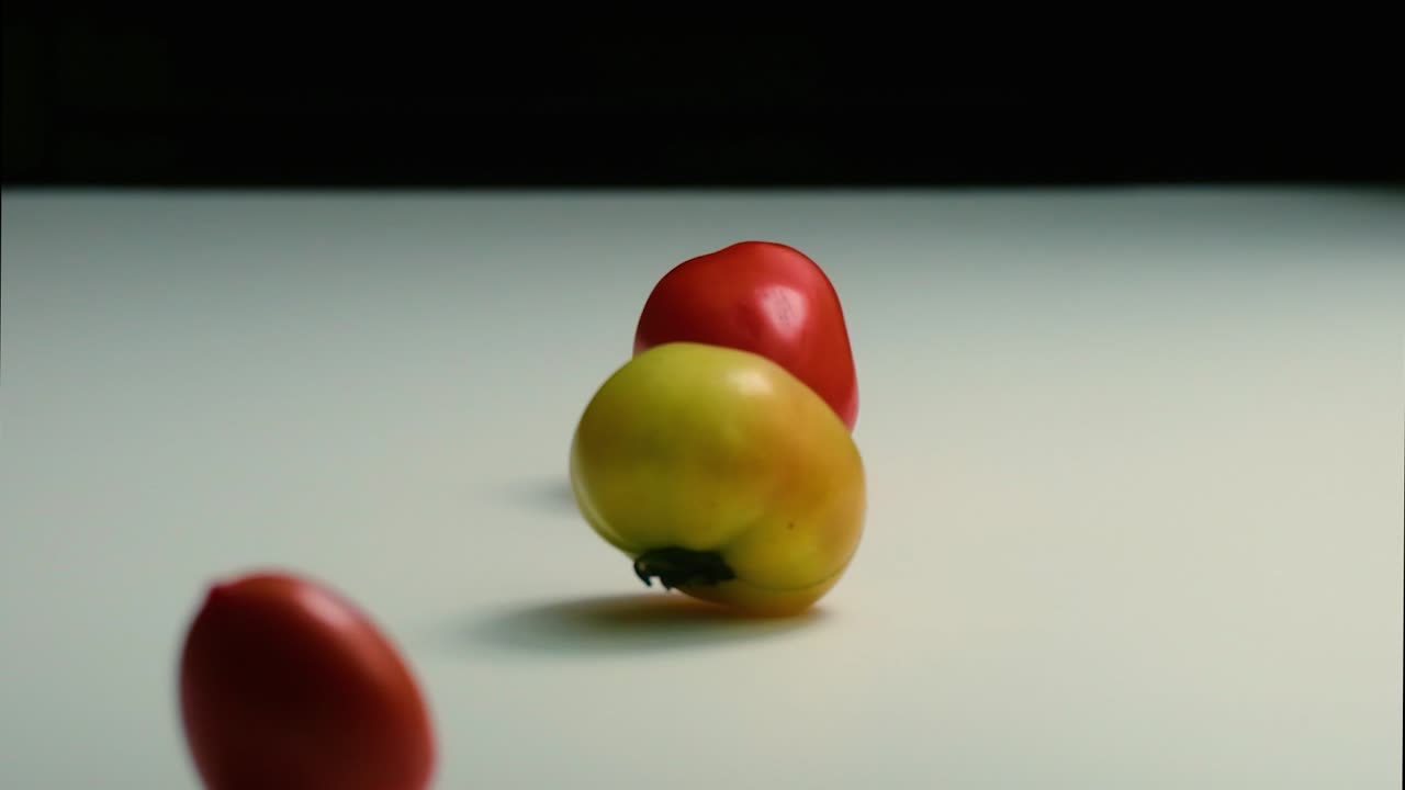 Traditional tomato, cherry tomato, green and red, on white surface and black background