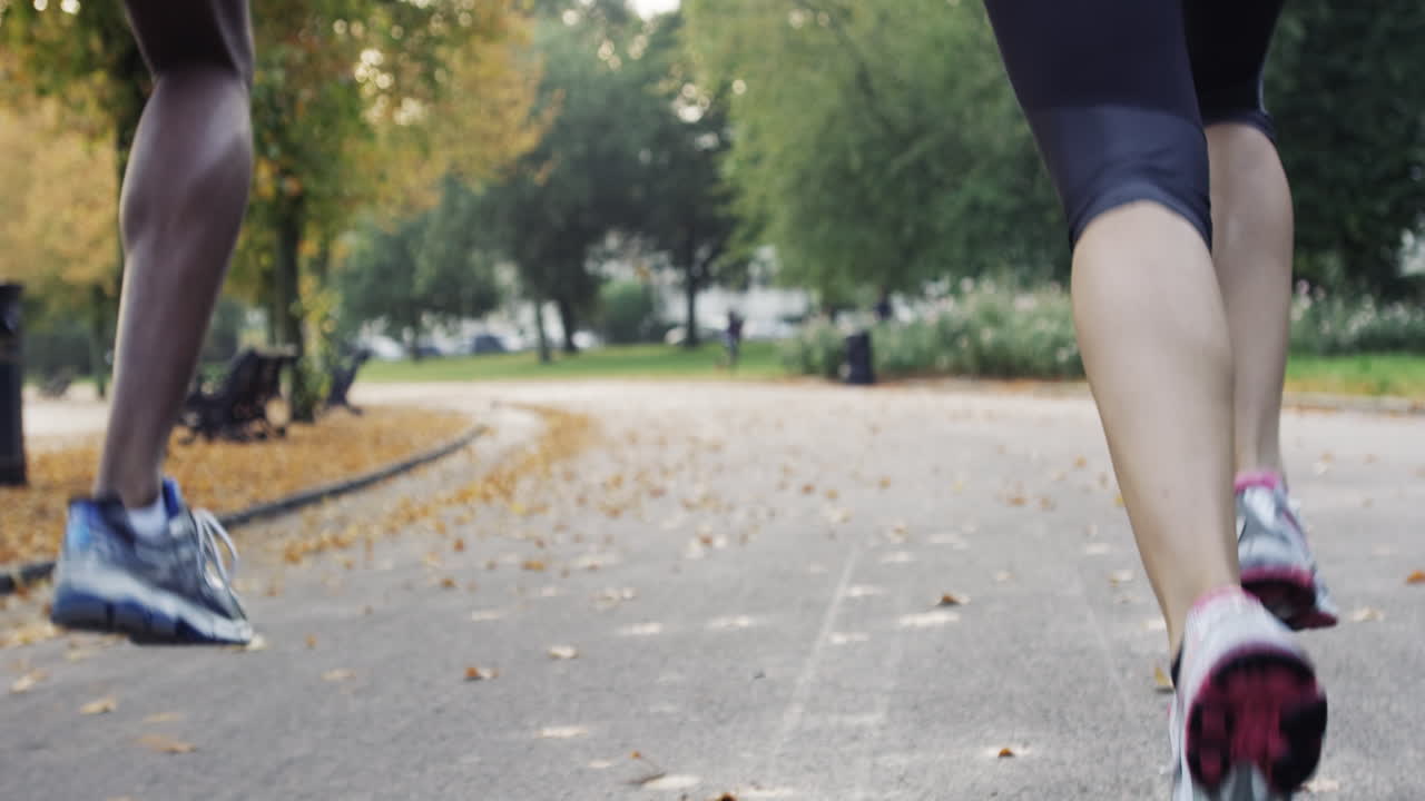 pareja atlética corriendo en el parque usando dispositivos conectados a la tecnología portátil