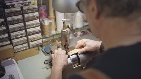 shoulders-view-of-a-leather-craftsman-while-thinning-leather-belt