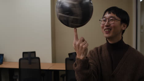 man spinning a ball on his finger in an office