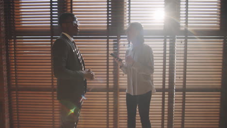 multiethnic male and female colleagues speaking in office