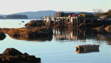 rocks and a pier are near a lobster village in stonington maine at sunset