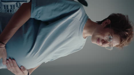 pregnant woman stroking her belly and looking through the window with smile
