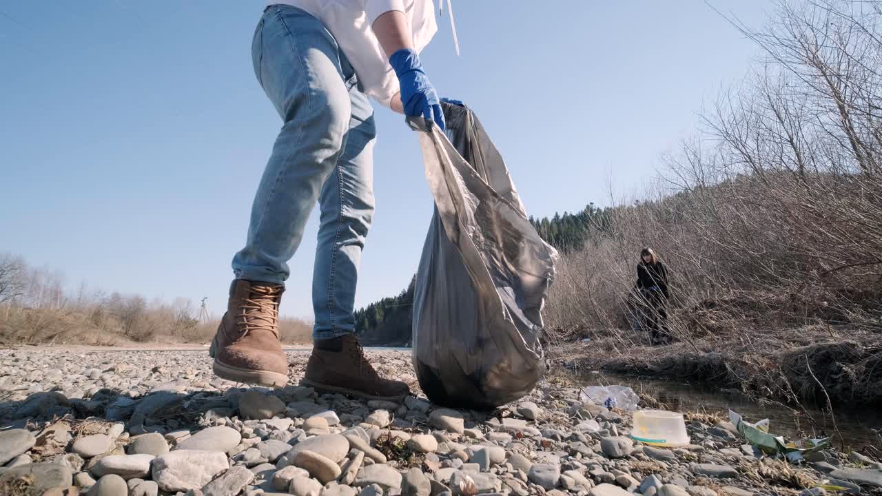 trabajo en equipo limpiando plástico en la playa. voluntarios recogen basura en una bolsa de basura. contaminación plástica y concepto de problema ambiental. limpieza voluntaria de la naturaleza del plástico. ecologización del planeta