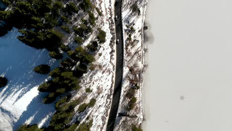 aerial drone view: snow covered bavarian alps mountain pass, cars driving scenic route with birds eye view of winter wonderland and majestic landscape