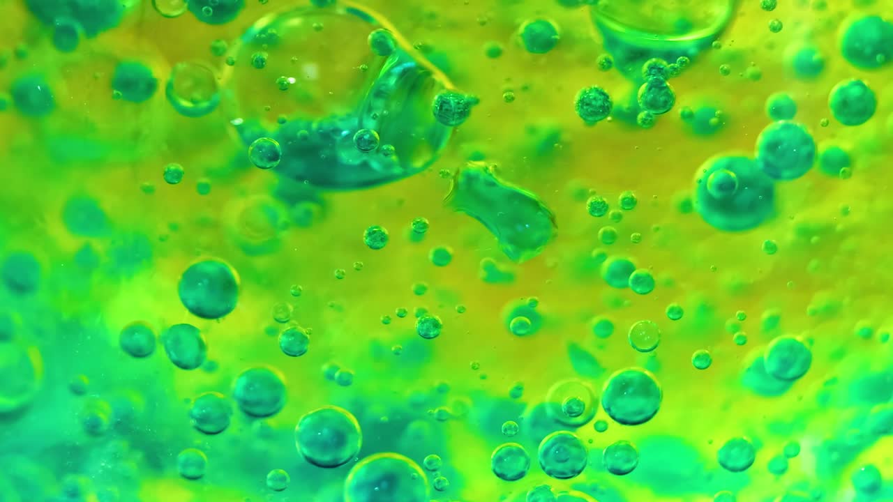 Dynamic bubbles in green and yellow hues create mesmerizing patterns in a fluid environment.