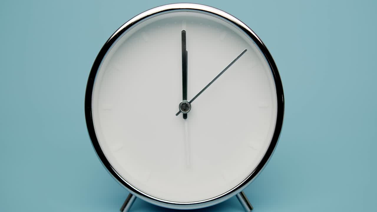 Alarm clock isolated on blue background Showtime 12.00 am or pm.
