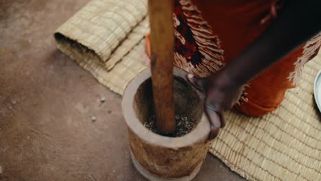 Kaffeebohnen,-Die-Von-Einer-Afrikanerin-Manuell-Mit-Hölzernem-Stößel-Und-Mörser-Zerstoßen-Wurden