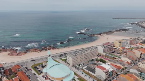 Aerial-view-of-Caxinas-beach,-church,-and-coastal-town-in-Vila-do-Conde,-Portugal