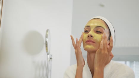 mujer caucásica mirándose en el espejo y haciendo maquillaje en el baño
