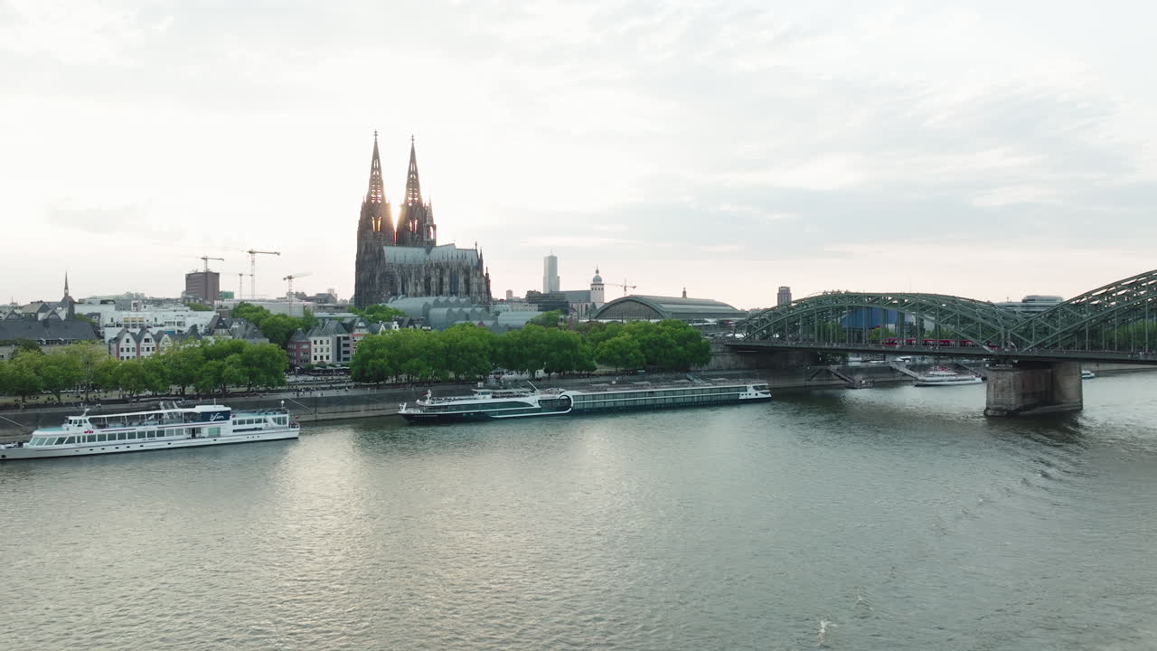 drone filma un barco en el rin, el dron se mueve hacia arriba y puedes ver la catedral de colonia en la puesta de sol, un tren conduce en el puente hohenzoller sobre el rin
