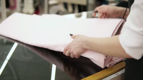 Apunte-Imágenes-De-Hermosas-Manos-Femeninas-Desplegando-Un-Rollo-De-Tela-Ligera-Capa-Por-Capa.-Mide-La-Longitud-Con-Un-Centímetro.-Tienda-De-Telas