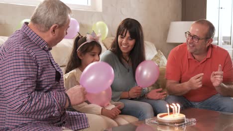 family singing happy birthday sitting on a sofa