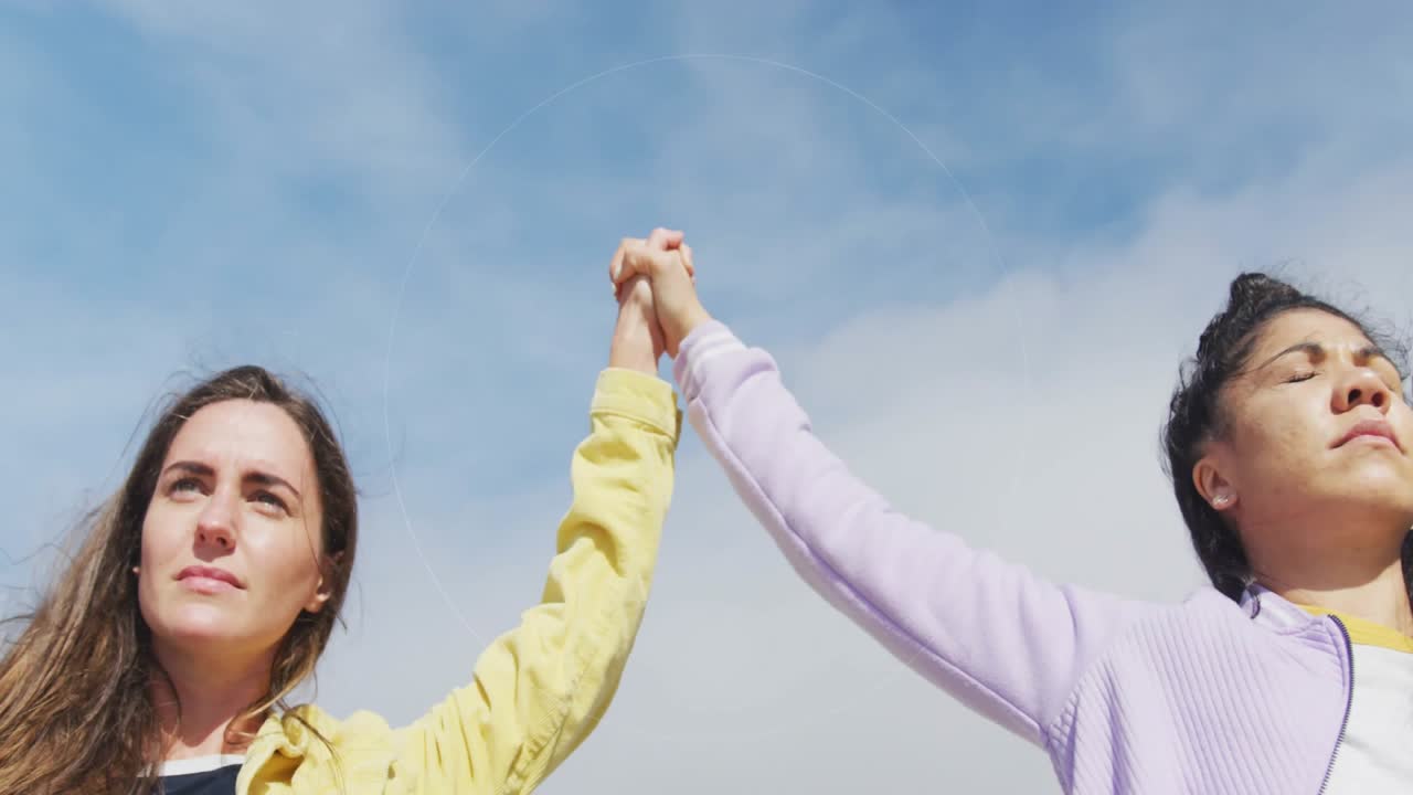 Amici che si uniscono per mano in segno di unità, formando un cerchio e osservando l'orizzonte sotto un cielo blu, in un contesto tecnologico.