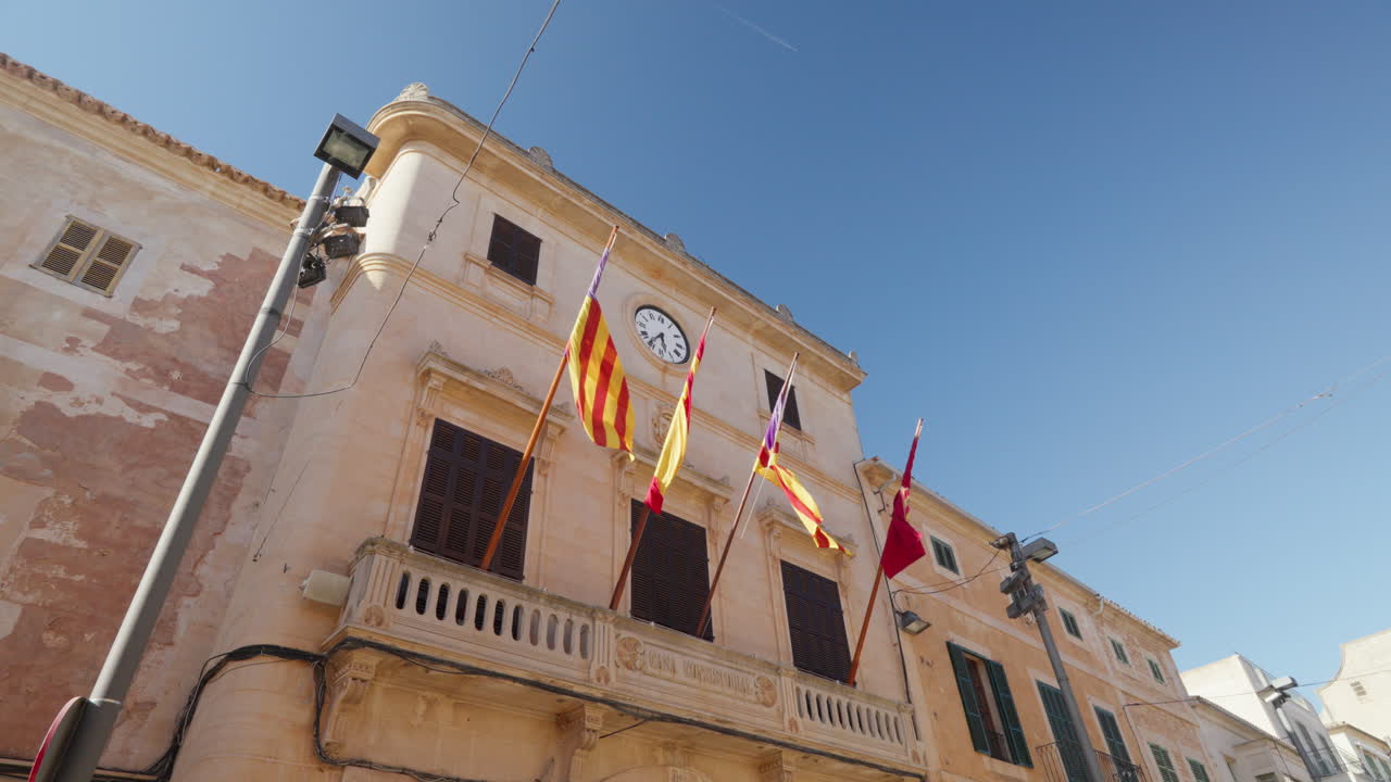 Balai kota bersejarah dengan bendera di bawah langit biru cerah di Santanyi, Mallorca.