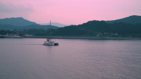 Barco-Catamarán-Navegando-En-El-Océano-Durante-La-Puesta-De-Sol-Con-Cielo-Rosa-En-El-Fondo