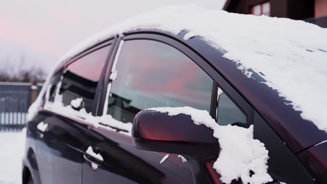Snow-covered parked car with frozen windshield wipers and side mirror clumped with slush. Cold winter morning vehicle cleaning and driving safety concept