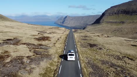 white campervan driving at an scenic road at feroe islands