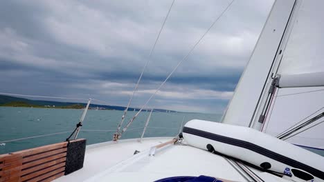 vela de proa encadenada en el barco - navegando en el mar bajo un cielo dramático - toma amplia