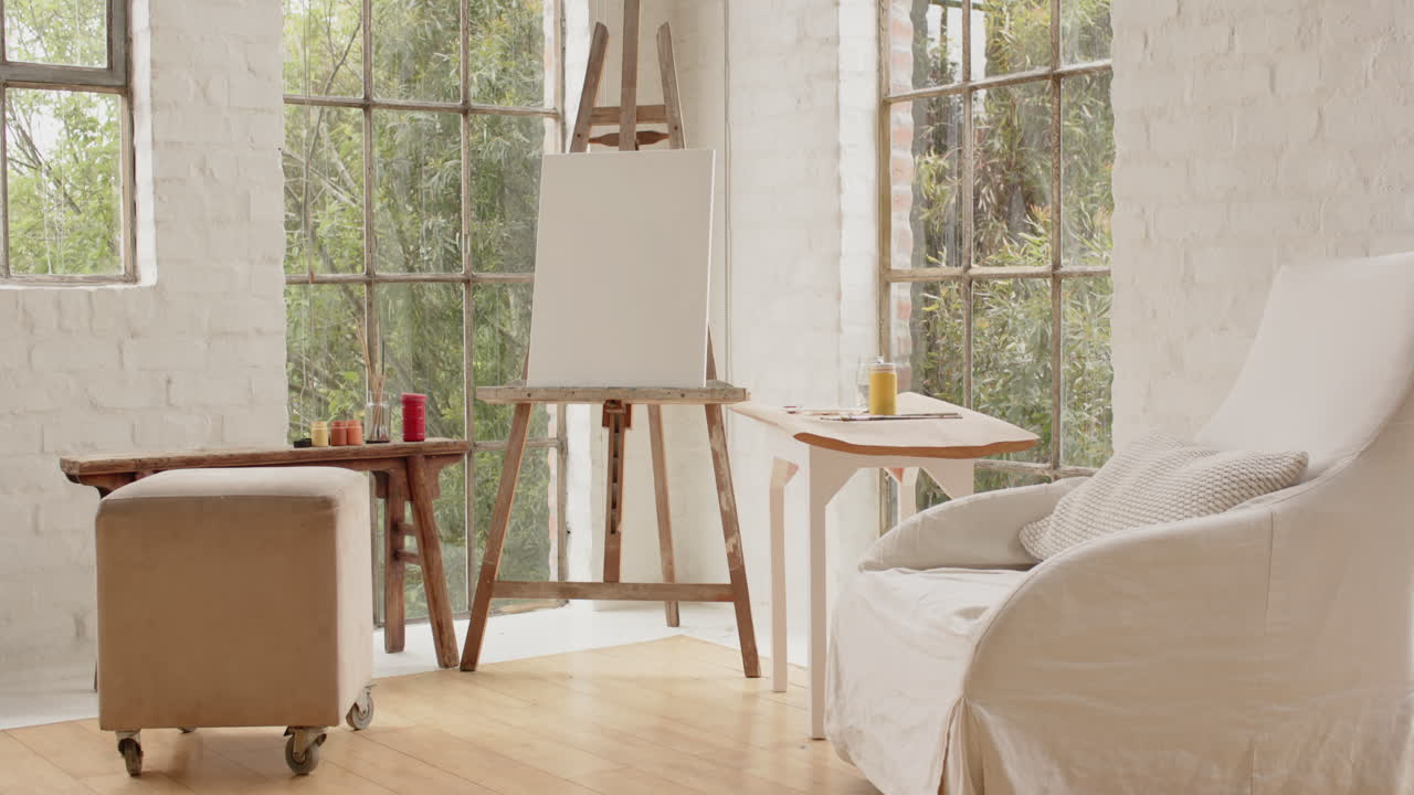 Cozy art home studio with blank canvas and paints by large windows
