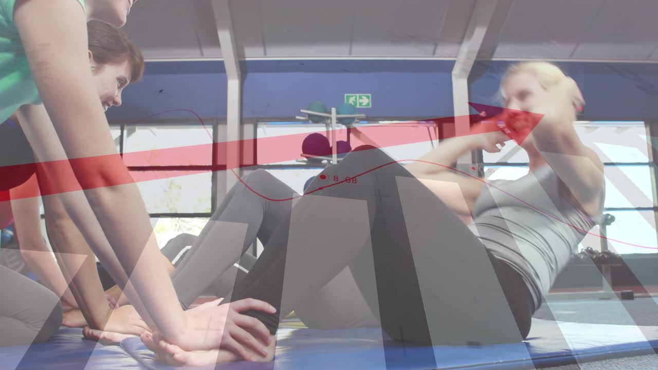 Two women doing crunches on blue mat, partner bracing initiating core, red chart overlaying weights