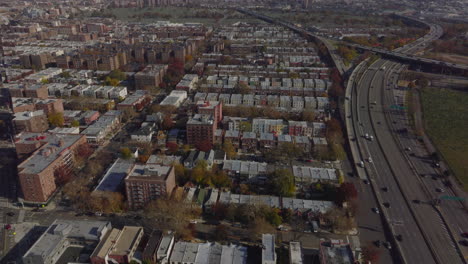 Filas-De-Edificios-Residenciales-En-Un-Barrio-Urbano-Cerca-Del-Intercambio-De-Autopistas-De-Varios-Carriles.-Toma-Panorámica-Aérea.-Reinas,-Ciudad-De-Nueva-York,-Estados-Unidos