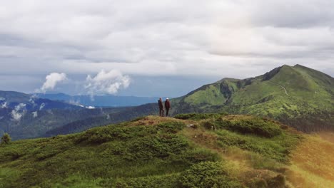 the man and woman standing on the mountain top with a beautiful view