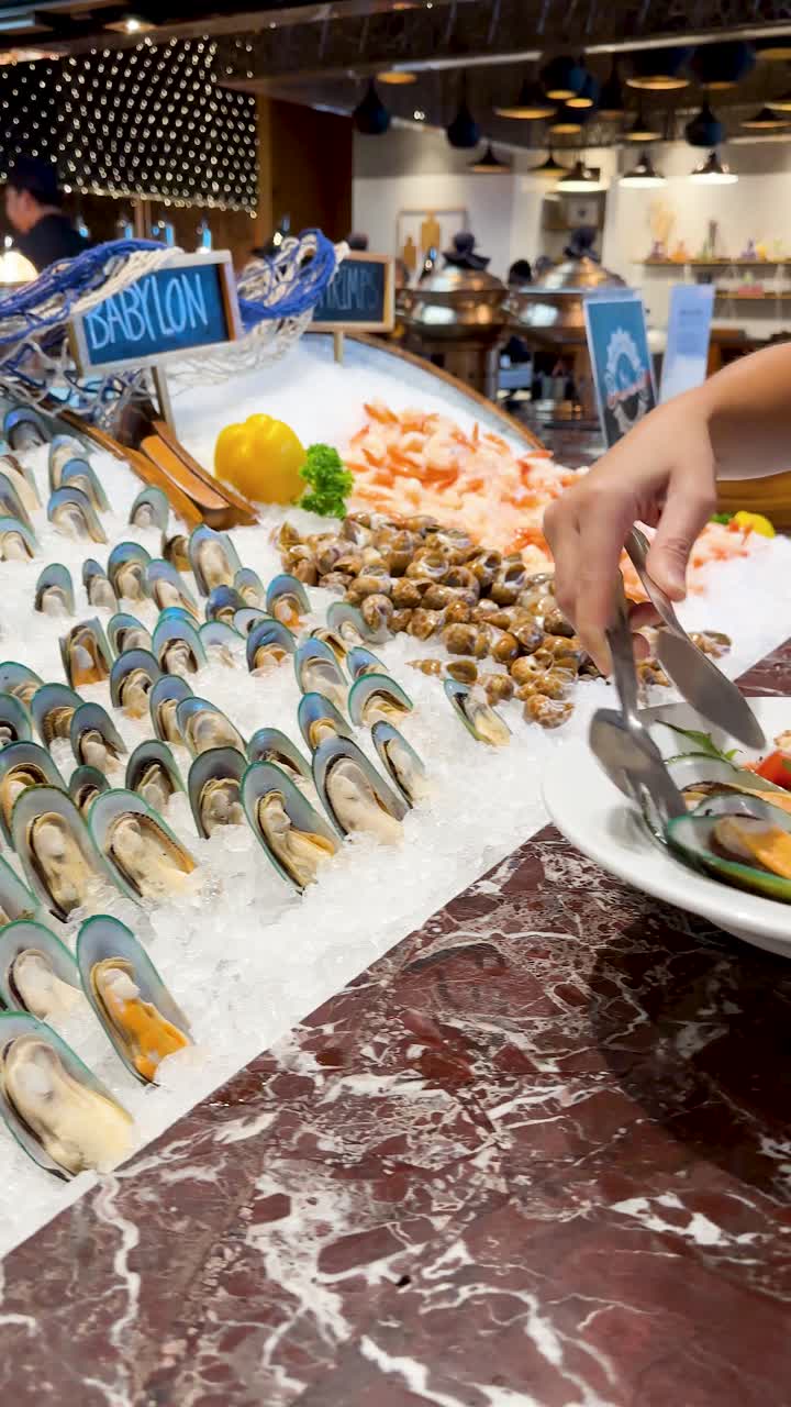 A person uses metal tongs to select fresh mussels from a chilled seafood ice display