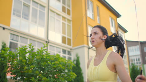 Entrenando-A-Una-Joven-Para-Saltar-La-Cuerda-Contra-Una-Casa-En-Un-Entorno-Urbano.-Saltando-Cuerda-En-El-Parque-A-Cámara-Lenta.-Una-Mujer-Entrena-Sola-Con-Una-Cuerda