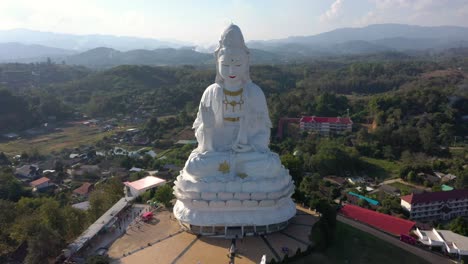 aerial drone of wat huay pla kang huge white big statue and pagoda with mountains and landspace in chiang rai, thailand