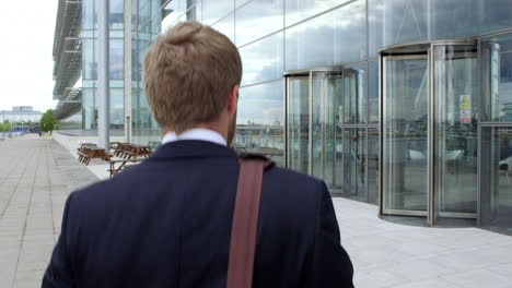 happy young businessman walking with coffee in a city street