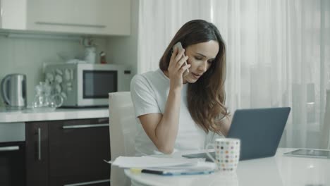 Young-woman-call-phone-at-home-kitchen.-Business-woman-talking-mobile-phone