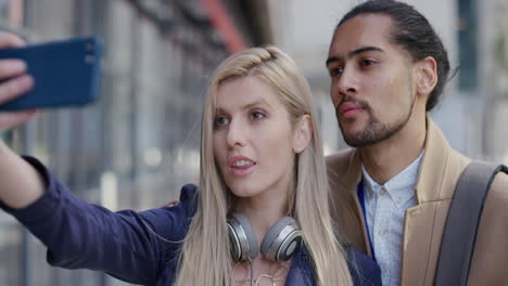 retrato de una joven pareja multiétnica tomando una foto selfie usando un teléfono inteligente posando haciendo caras divertidas disfrutando de un estilo de vida urbano feliz en cámara lenta serie de personas reales