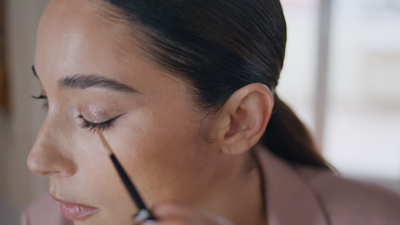 mujer de primer plano aplicando maquillaje de delineador de ojos en el interior de la habitación. cara de dama dibujando ojos