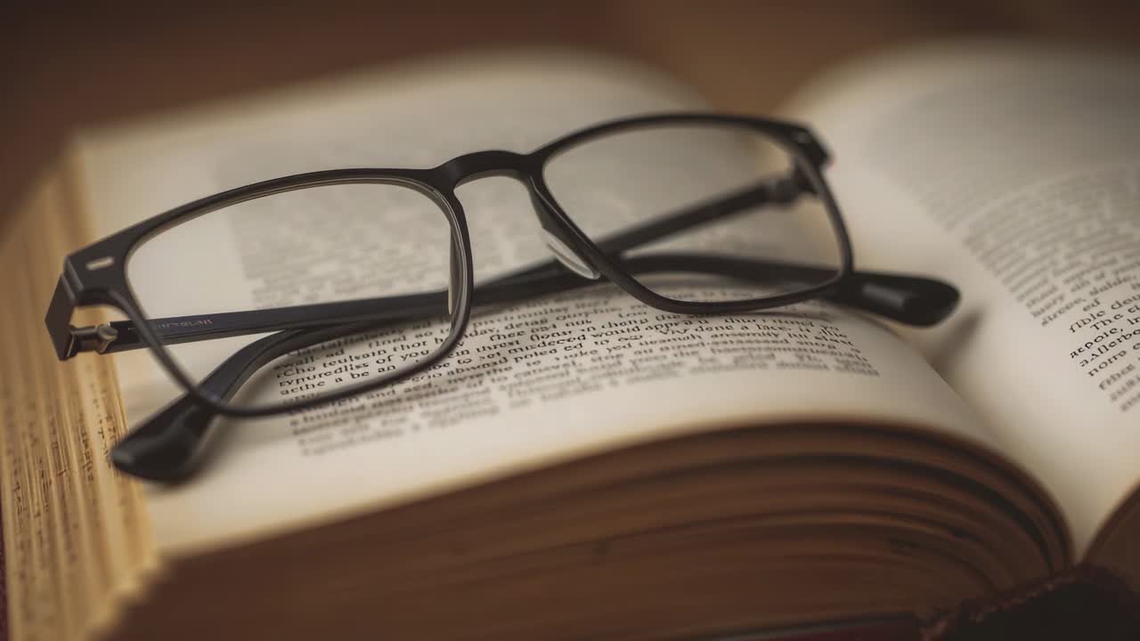 Pulling camera focus revealing black rectangular frames on open book to show text, warm light