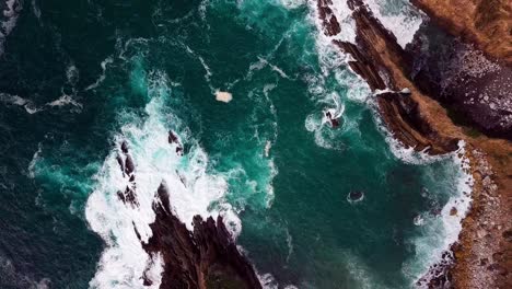 ocean waves flow into narrow cove in big sur cali, wide overhead drone shot