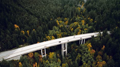 epic highway mountain bridge through a forest with cars traveling in fall, vancouver bc