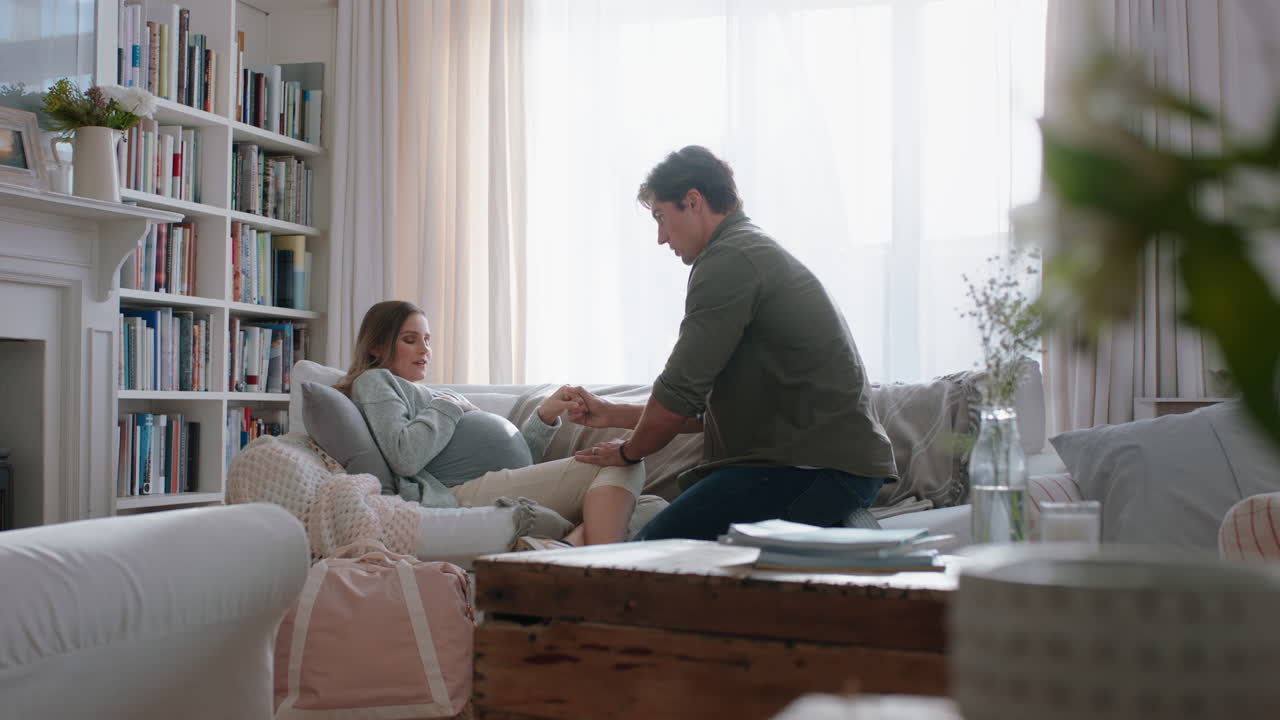 임신 중인 젊은 여성이 수술을 받고 있습니다. 긴장된 남편이 아내를 도와서 임신 통증을 통해 침착하게 숨을 쉬고 있습니다. 집에서 소파에서 휴식을 취하고 있습니다.