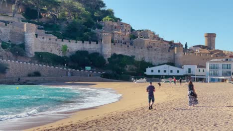 Tossa-de-Mar-bay-seen-from-the-castle-to-the-beach-with-coarse-sand-and-turquoise-blue-sea-water-old-walled-medieval-fishing-village-Mediterranean-sea