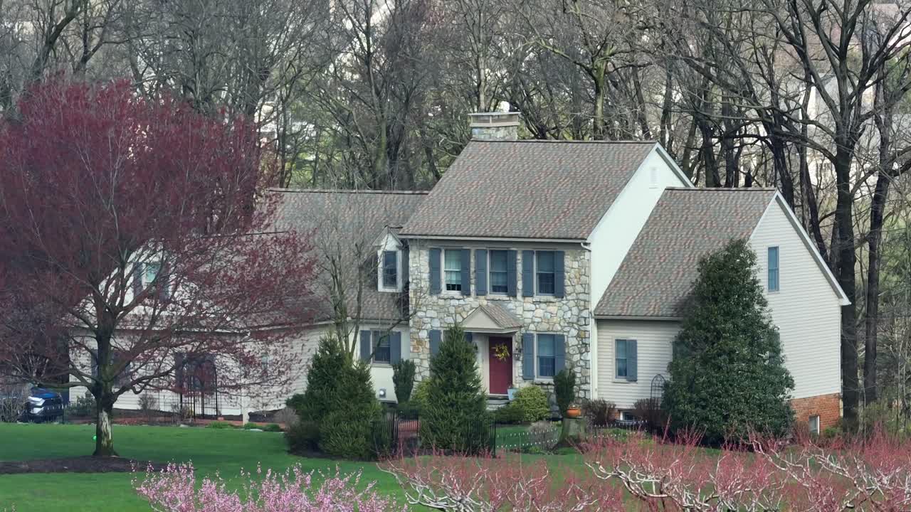 Aerial view of a picturesque suburban home with a well-manicured lawn and surrounding orchard trees blooming in spring, highlighting the beauty of residential architecture and landscaping in the USA.