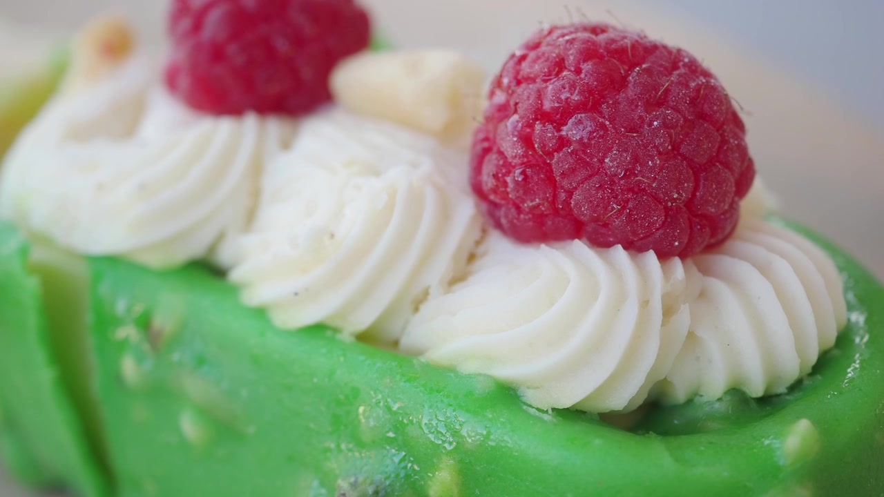 Close-up of a Fork Cutting into a Green Dessert with Raspberries