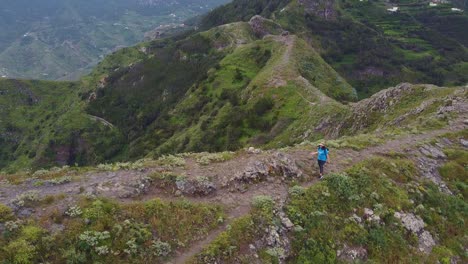 Epic-steep-mountain-cliffs-and-Caucasian-female-hiking-at-Roque-de-Taborno-in-Tenerife,-Canary-Islands,-Spain---aerial-view