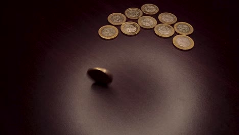 10 pesos coin spinning by hand on a wooden table