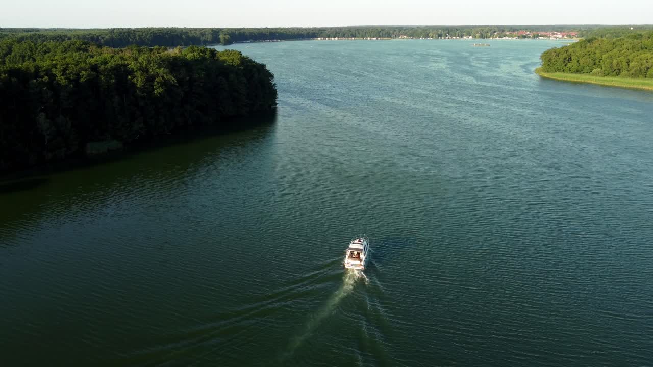 pequeño yate conduciendo en un lago rodeado de un bosque en brandeburgo, alemania