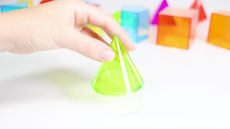 hands manipulate vibrant 3d geometric shapes on a white surface, emphasizing educational play and tactile learning