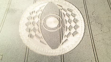 aerial descent with view of eye-shaped crop circle in dry brown farm land