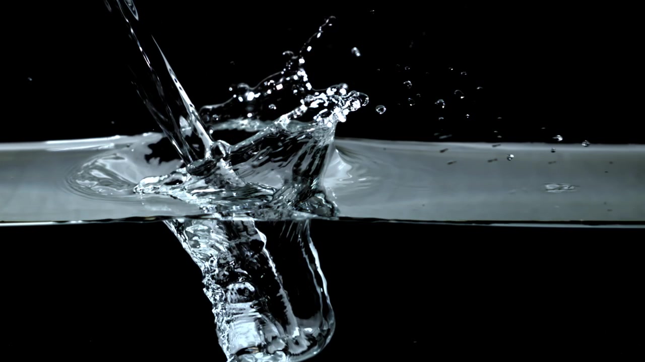 Movimento rallentato di acqua limpida che si versa e schizza su sfondo nero.