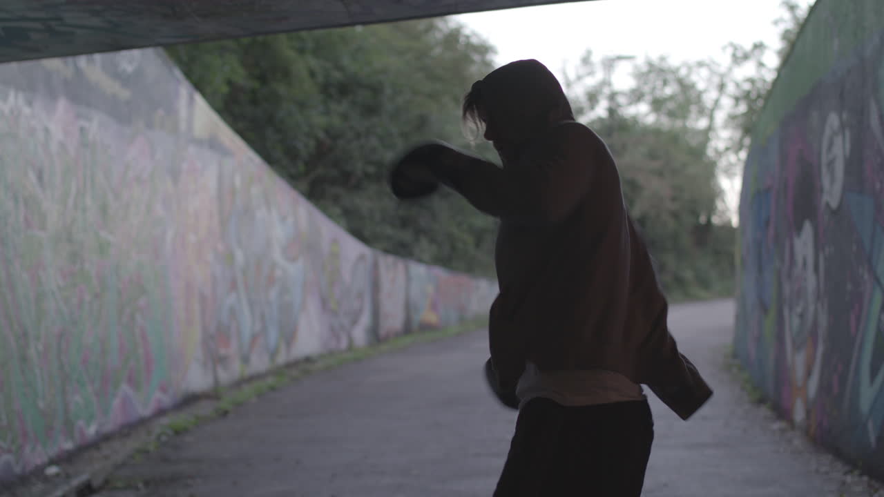 plano general de jóvenes atraer hombre boxeo en paso subterráneo, en cámara lenta